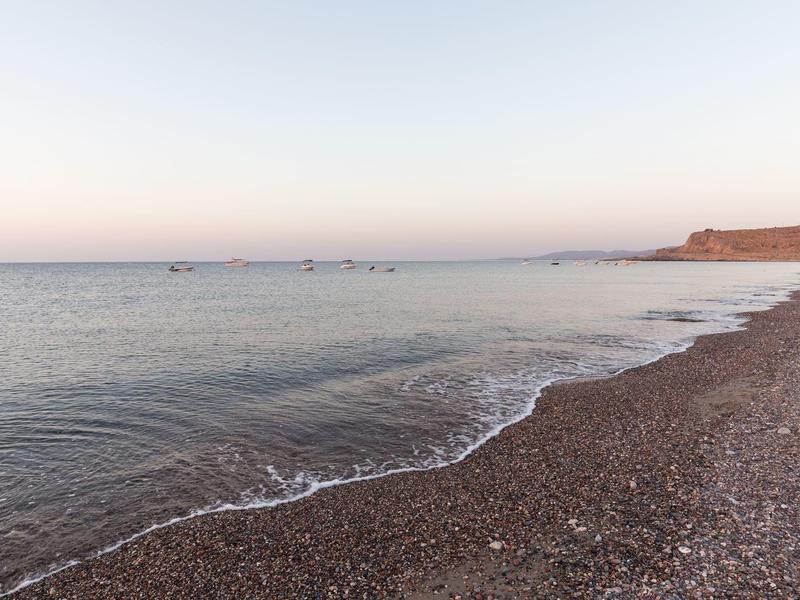 Spiaggia di ciottoli con mare calmo al tramonto