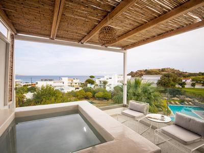 Überdachte Terrasse mit Jacuzzi, zwei Liegestühlen, Pool und Blick auf grüne Landschaft und Meer.