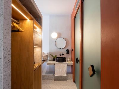 Moderner Hotelbadezimmerbereich mit Holzschrank, Spiegel und Waschtisch in ruhigen Farben.