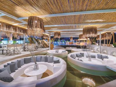 Área lounge moderna con sofás blancos redondos y techo de madera en un hotel.