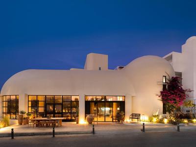 Edificio bianco a cupola al crepuscolo con luci calde e area salotto davanti.