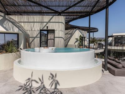 Runder Außenwhirlpool auf Terrasse mit modernen Sitzplätzen unter blauem Himmel.
