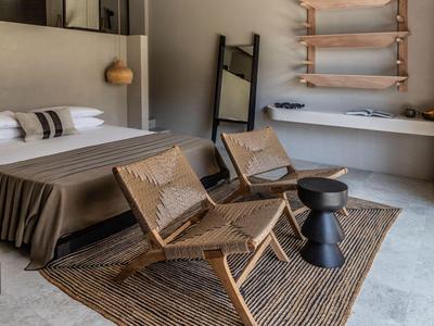 Modernes Hotelzimmer mit Doppelbett, zwei Holzstühlen und Teppichboden.