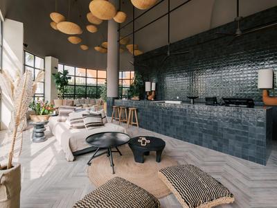 Modernes Hotellobby mit hohen Decken, Sitzbereichen und einer langen Theke aus dunklem Stein.
