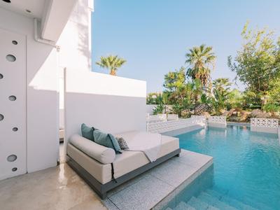 Moderner Außenbereich mit Sofa und Pool, umgeben von Palmen und klarem Himmel.