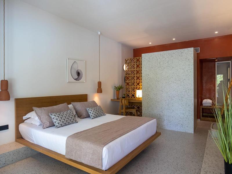 Camera d'hotel moderna con letto matrimoniale, accenti in legno e atmosfera rilassata.