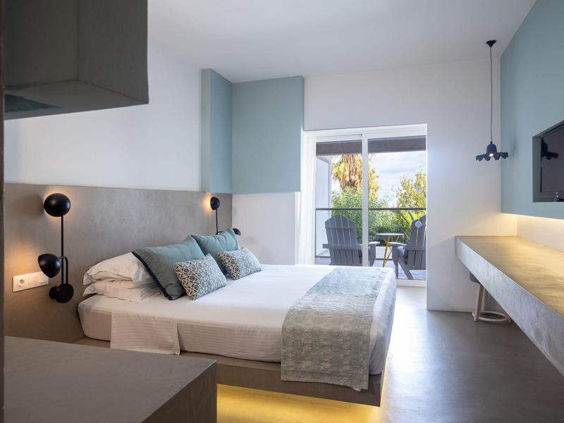 Camera d'hotel moderna con letto matrimoniale, balcone e decorazioni eleganti in tonalità di blu.