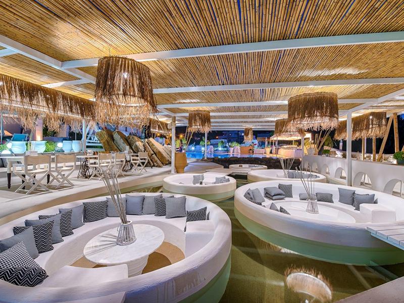 Aree lounge rotonde moderne con cuscini e lampade di bambù in un elegante hotel sulla spiaggia aperto.