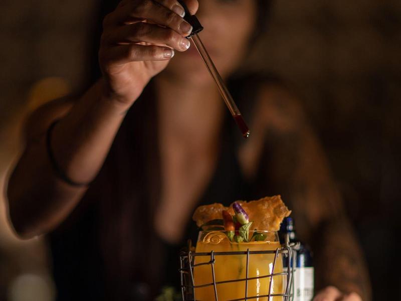 Un cameriere decora un cocktail con una fetta d'arancia usando un contagocce.