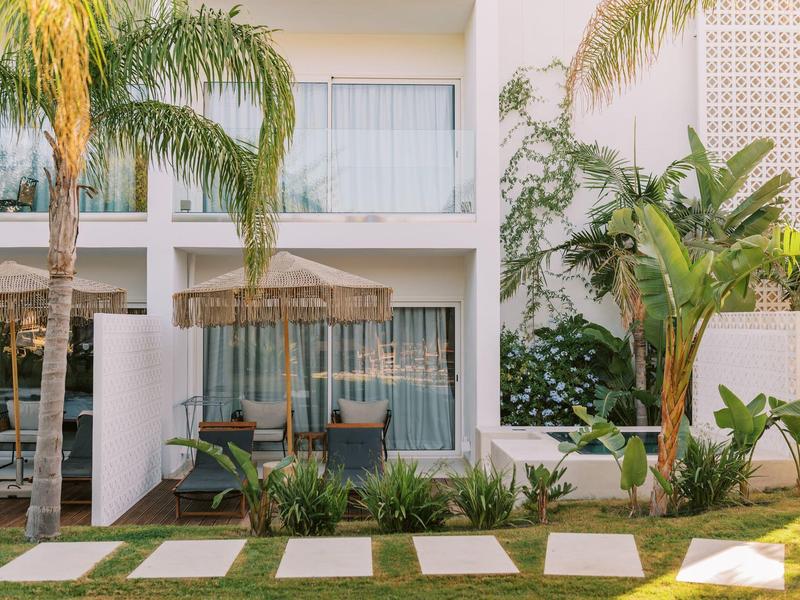 Hotel moderno con piante tropicali e terrazza in un ambiente soleggiato.