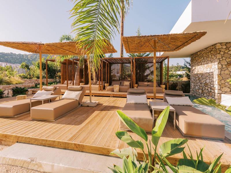 Area esterna moderna con terrazza in legno, mobili lounge e palme.