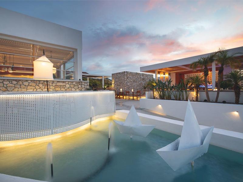 Terrazza moderna con piscina e decorazioni origami sotto un cielo al tramonto.