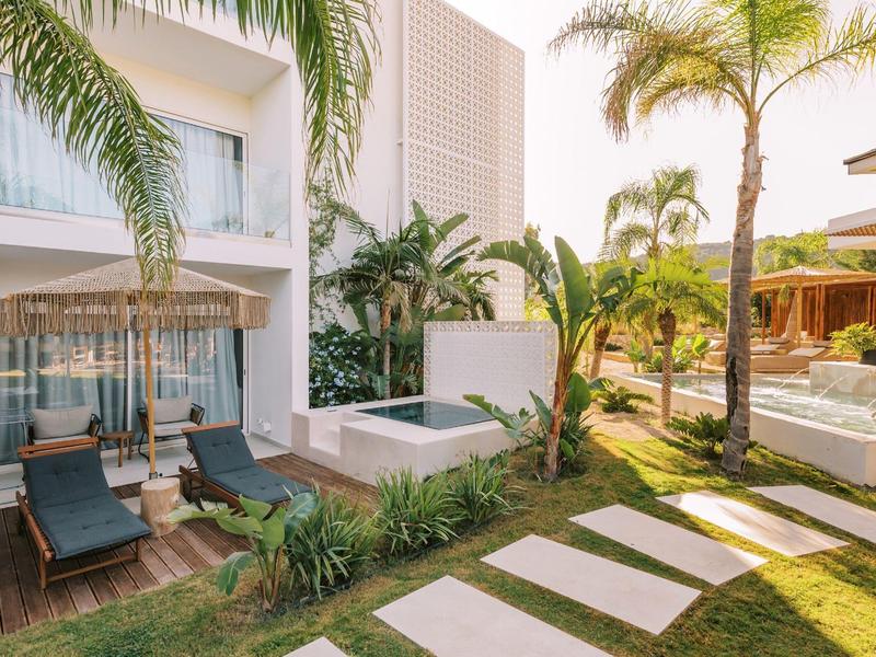 Giardino moderno dell'hotel con sdraio, palme e comode aree salotto all'aperto.