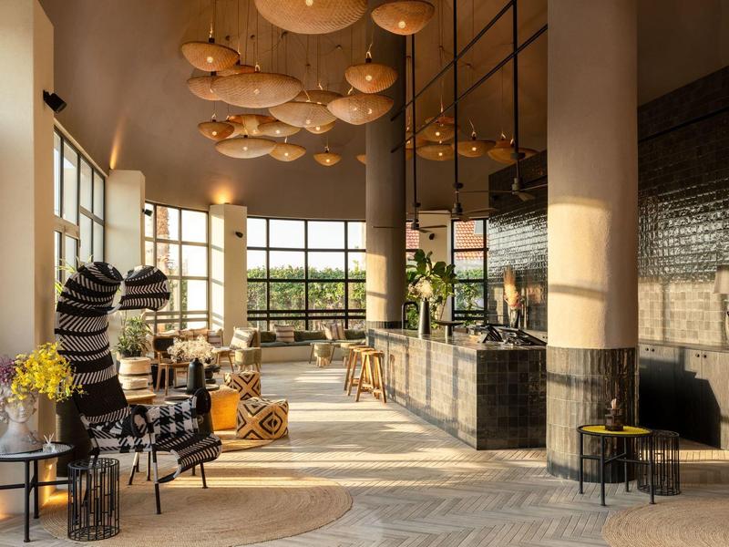 Hall dell'hotel moderno con grandi finestre, luci luminose e aree salotto eleganti.