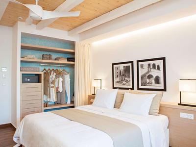 Camera d'hotel moderna con letto matrimoniale, armadio aperto e illuminazione elegante.