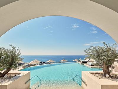 Basen typu infinity z widokiem na morze i parasolki pod niebieskim niebem