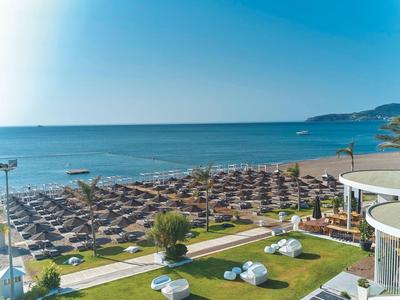 Vista di una spiaggia con molti ombrelloni e lettini accanto al mare in giornata soleggiata.
