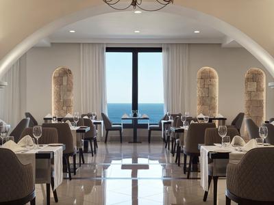 Ristorante elegante dell'hotel con vista sul mare attraverso una grande finestra e tavoli apparecchiati.