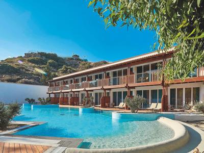 Hotel con piscina all'aperto davanti a una collina sotto un cielo blu sereno.
