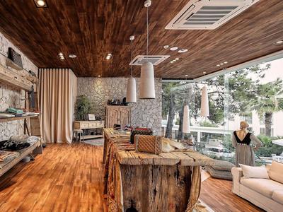 Salon z rustykalnymi drewnianymi meblami i dużą szklaną ścianą z widokiem na ogród w hotelu