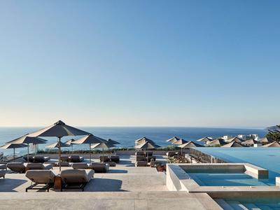 Luksusowy basen z leżakami i parasolami z widokiem na morze