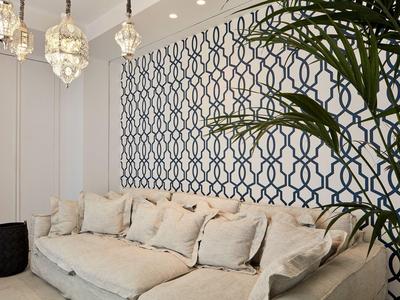 Divano beige con cuscini davanti a una parete decorata e una pianta interna.