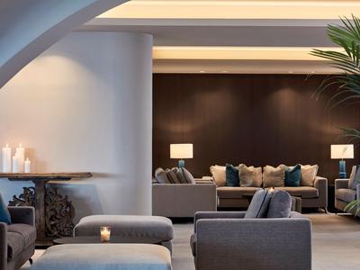 Nowoczesna strefa lounge hotelu z wygodnymi fotelami, sofami, nastrojowym oświetleniem i roślinami.