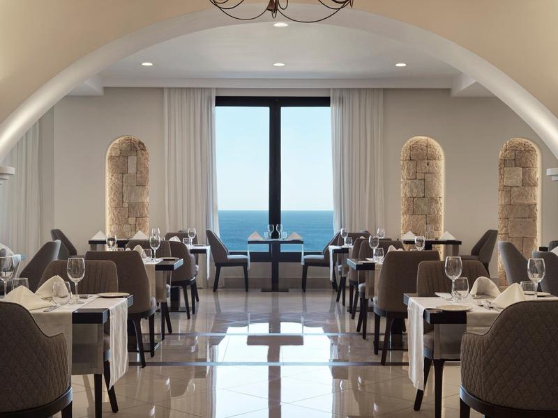 Ristorante elegante dell'hotel con vista sul mare attraverso una grande finestra e tavoli apparecchiati.
