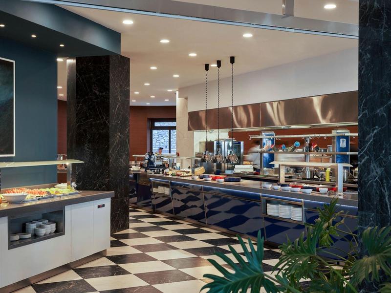 Area ristorante moderna in hotel con pavimento a scacchiera e zona bar.