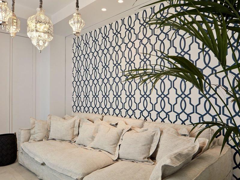 Divano beige con cuscini davanti a una parete decorata e una pianta interna.