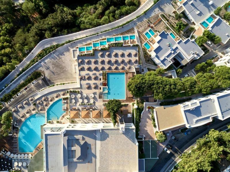 Vista aerea di un resort con diverse piscine, lettini e alberi