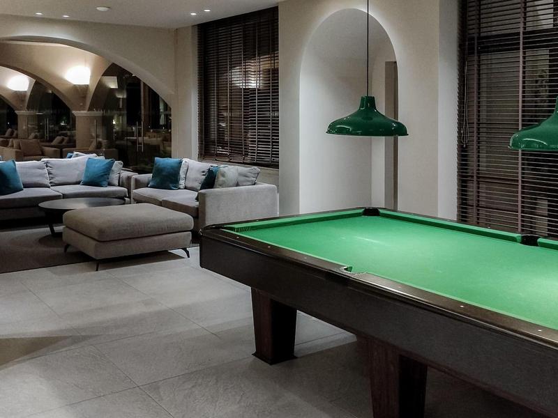 Area ricreativa moderna con tavolo da biliardo, divani accoglienti e illuminazione soffusa.