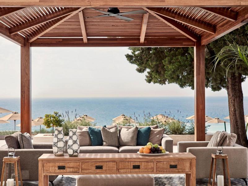 Accogliente salotto sotto una pergola in legno con vista mare e comodi posti a sedere.