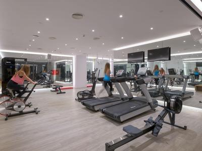 Moderne Fitnessstudio mit Laufbändern, Rudergeräten und mehreren Personen beim Training.