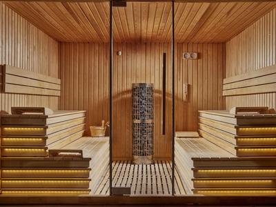 Sauna con rivestimento in legno, illuminazione calda e pietre al centro