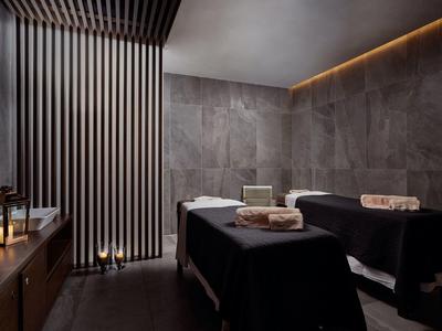 Elegante sala spa con due lettini da massaggio, luce soffusa e design moderno delle pareti.