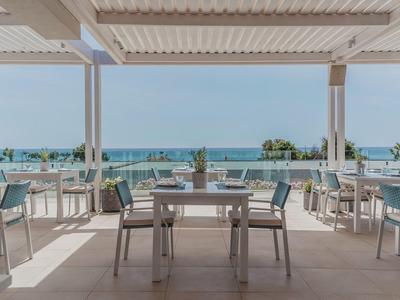 Area pranzo aperta con vista sul mare e terrazza in un hotel.