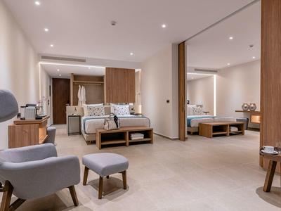 Area camera d'hotel moderna con posti a sedere, mobili in legno e illuminazione calda.