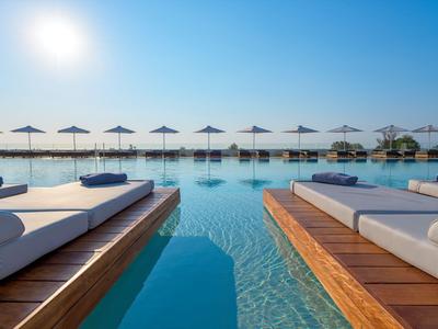 Luxuriöser Pool mit Liegen und Sonnenschirmen unter klarem Himmel im Resort.