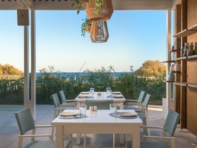 Hell eingerichtetes Restaurant mit Blick auf die Küste und das Meer bei Sonnenschein.