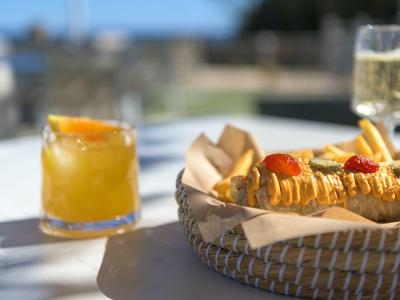 Un cestino di croissant e un bicchiere di succo d'arancia su un tavolo all'aperto con sfondo sfocato.