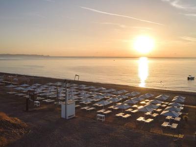 Spiaggia con lettini e ombrelloni al tramonto vicino al mare.