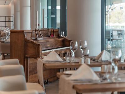 Elegantes Restaurantinterieur mit gedeckten Tischen und einem alten Klavier am Fenster.