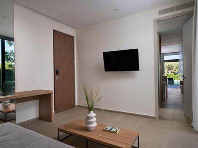 Schlicht eingerichtetes Hotelzimmer mit Schreibtisch, Tür, Wandfernseher und Balkonblick.