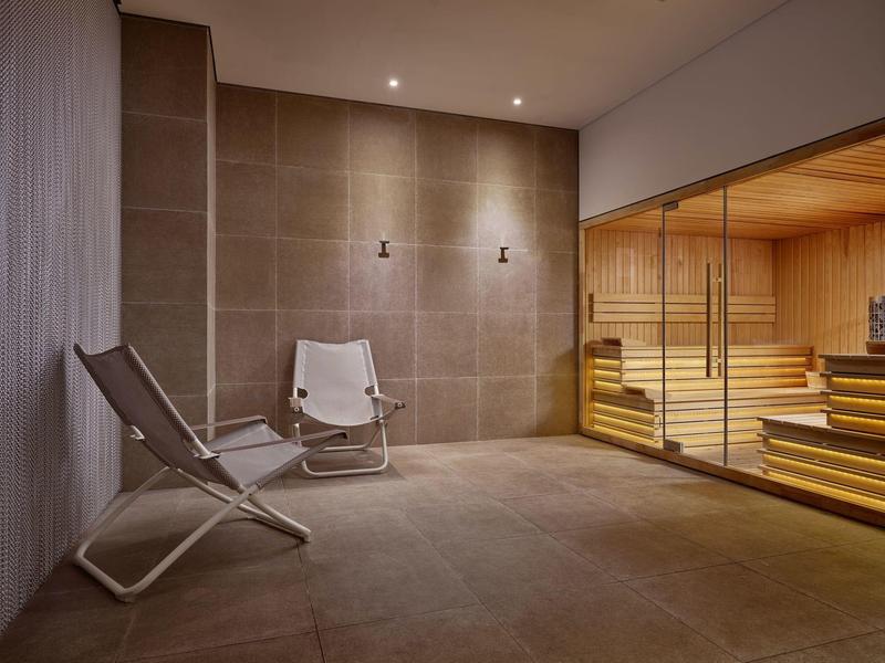 Sala sauna moderna con due poltrone e sauna rivestita in legno.