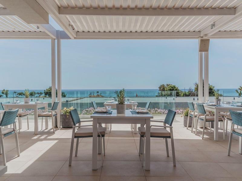 Area pranzo aperta con vista sul mare e terrazza in un hotel.