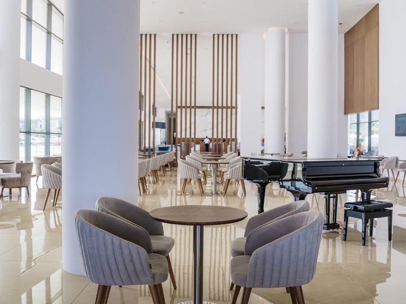 Interno moderno e luminoso con zona salotto e pianoforte a coda nero.