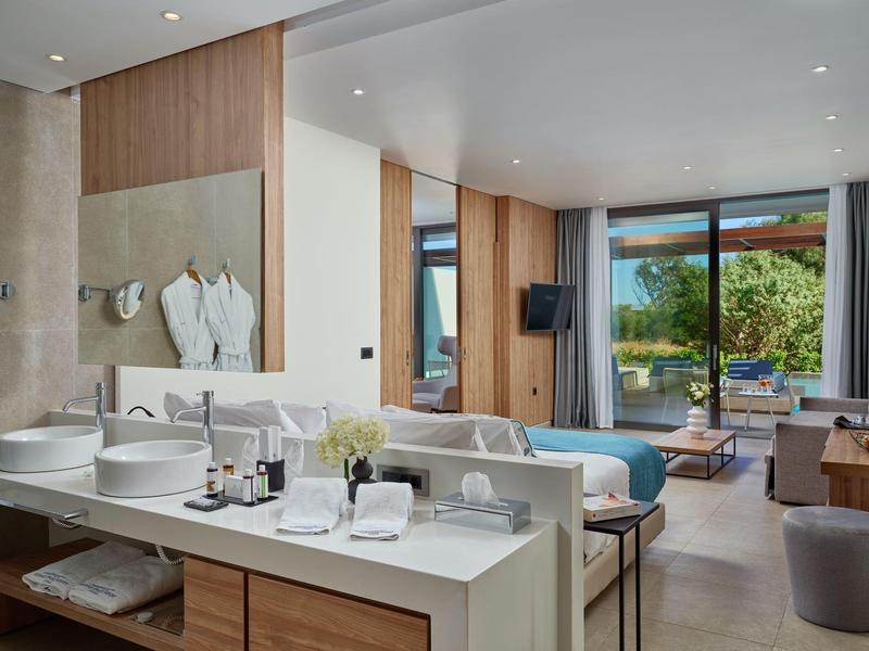 Camera d'hotel moderna con bagno aperto e vista sulla terrazza e piscina.