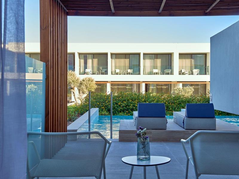 Balcone moderno dell'hotel con posti a sedere e vista sulla piscina e gli edifici bianchi