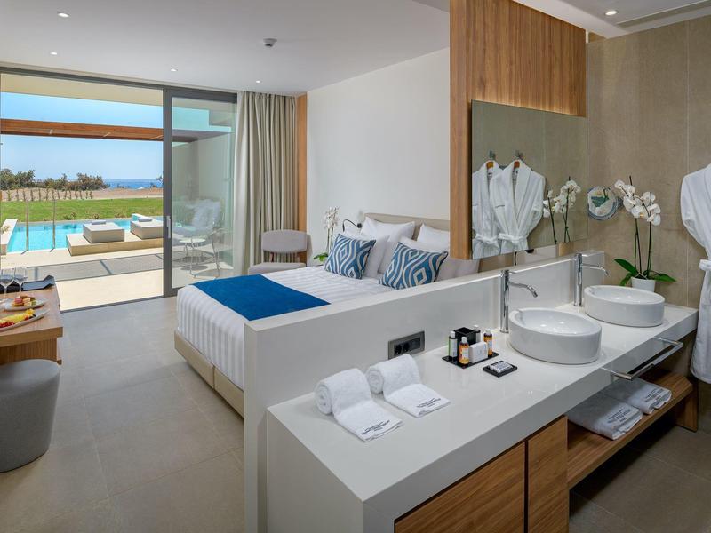 Camera d'hotel moderna con letto matrimoniale, bagno e terrazza con vista mare.